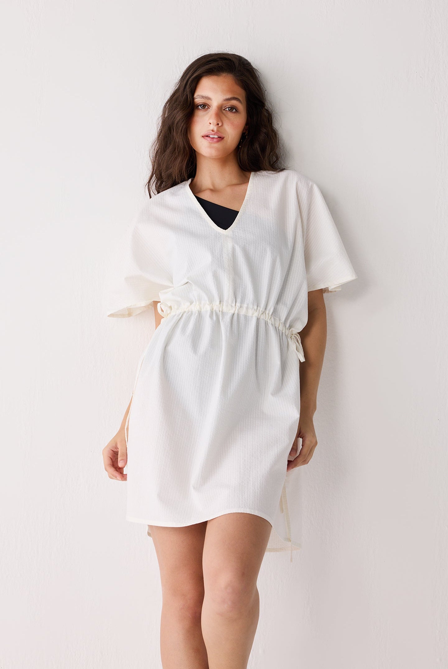 Woman wearing a white cover up against a plain background