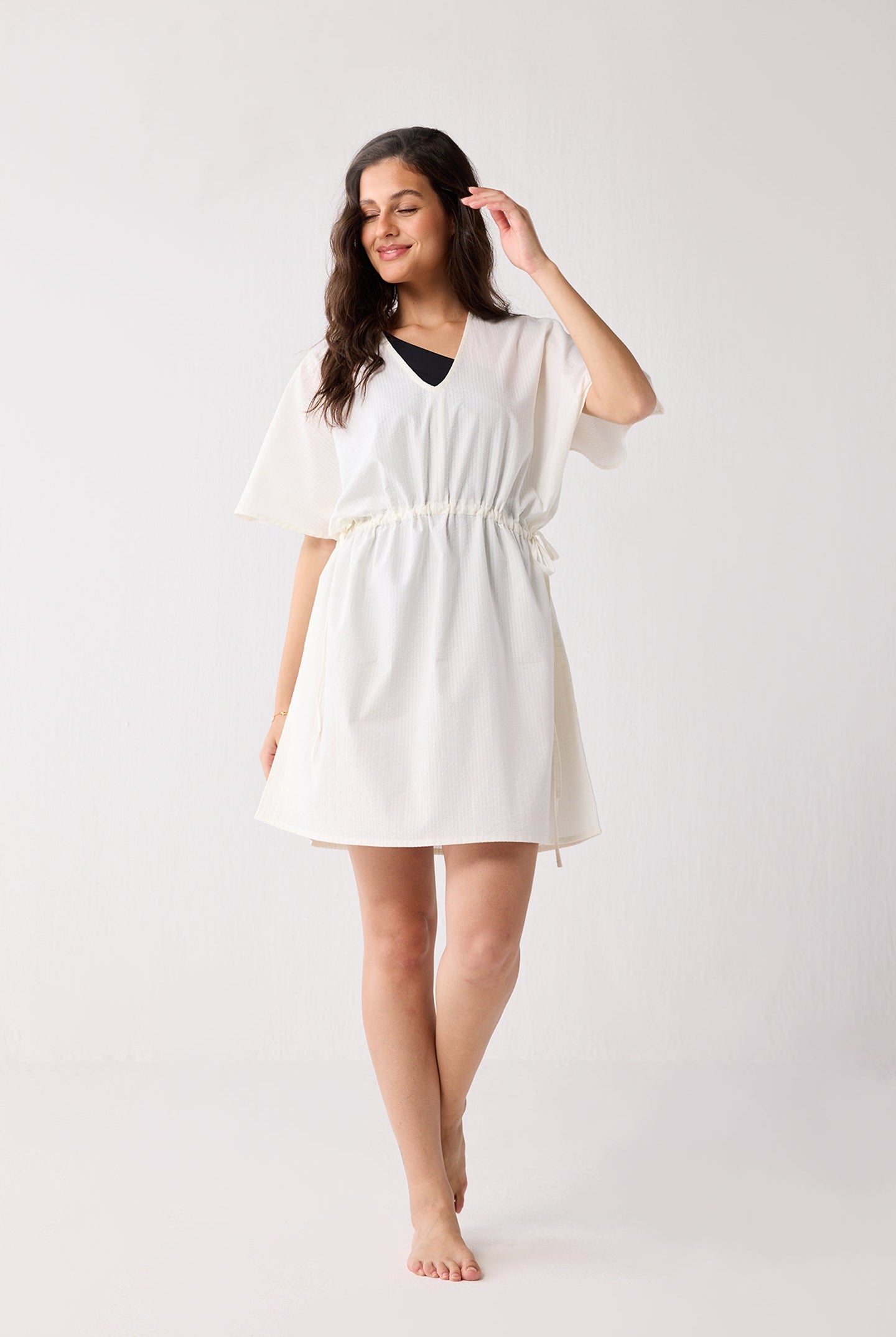 Woman wearing a white cover up against a plain background