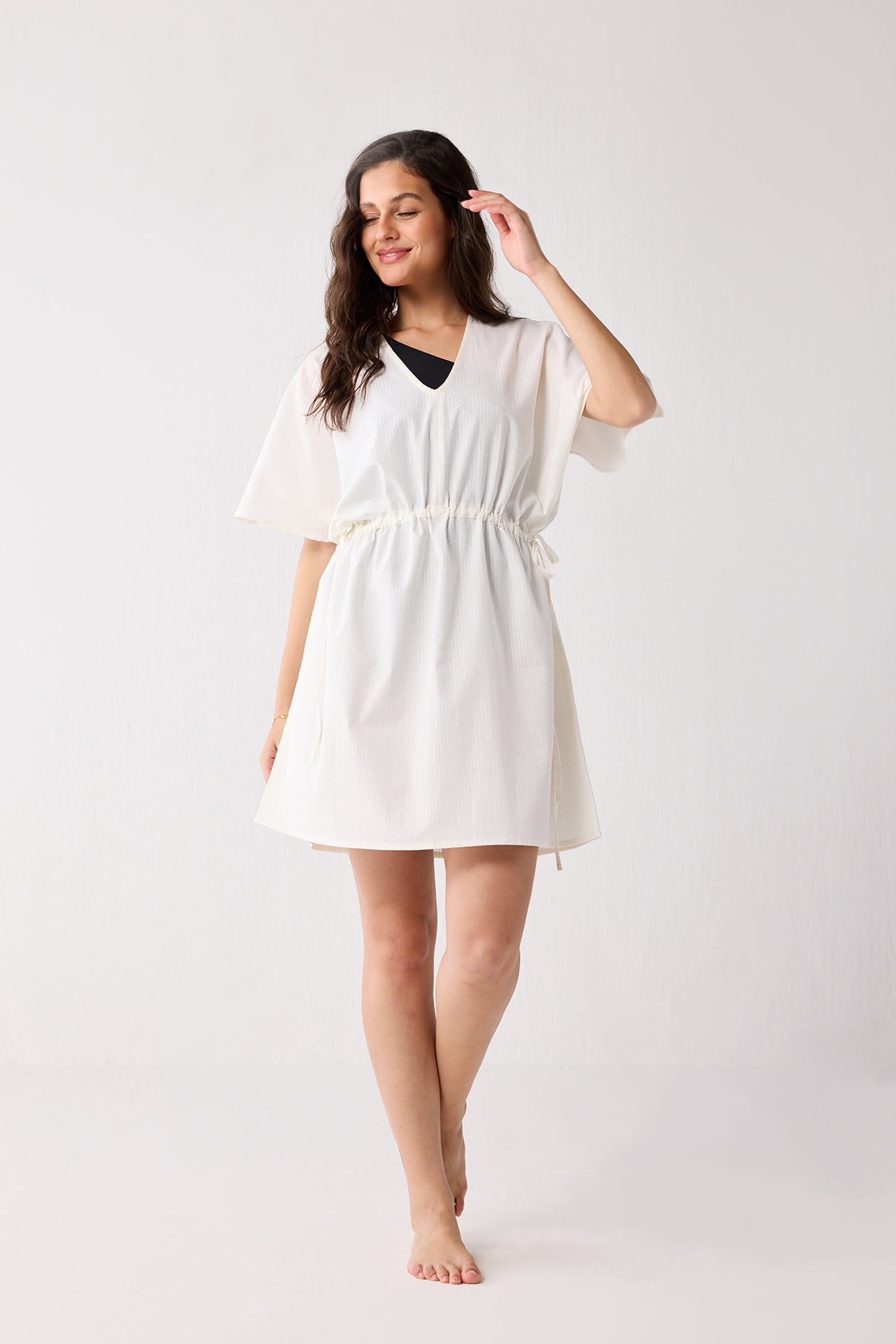 Woman wearing a white cover up against a plain background