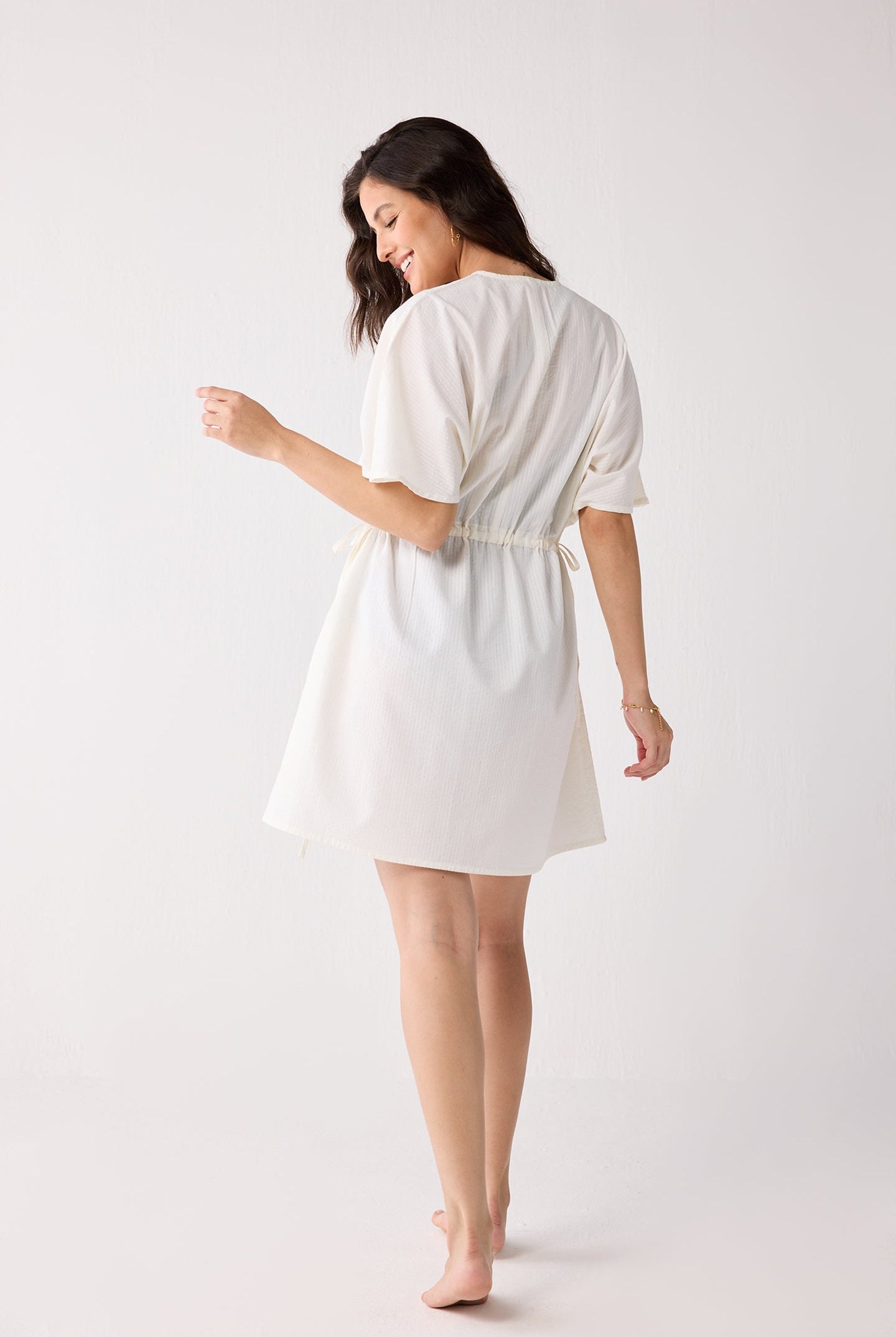 Woman wearing a white dress against a plain background