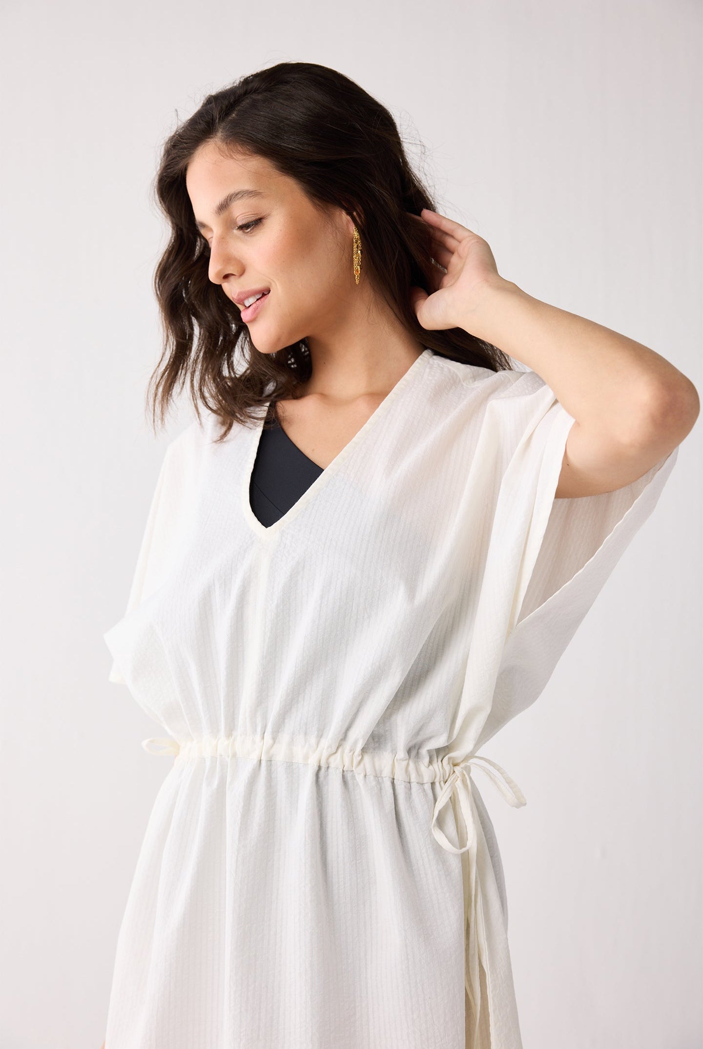 Woman wearing a white cover up against a plain background