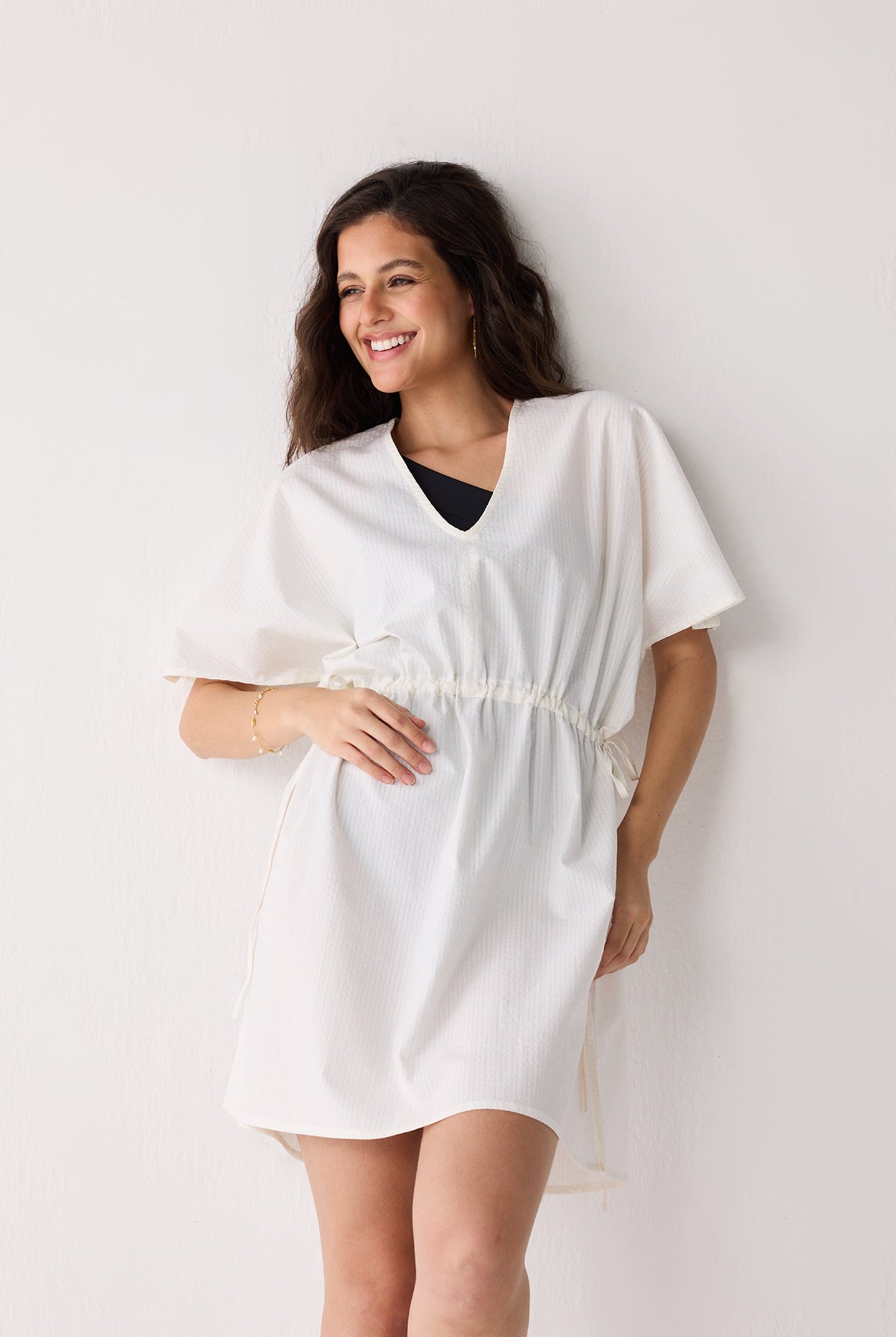 Woman wearing a white cover up against a plain background