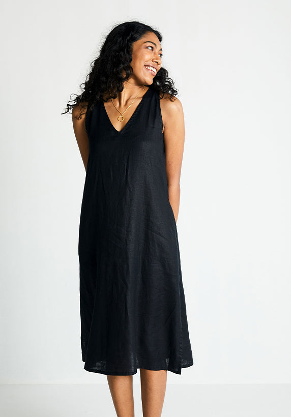 Woman wearing a black sleeveless dress against a plain background
