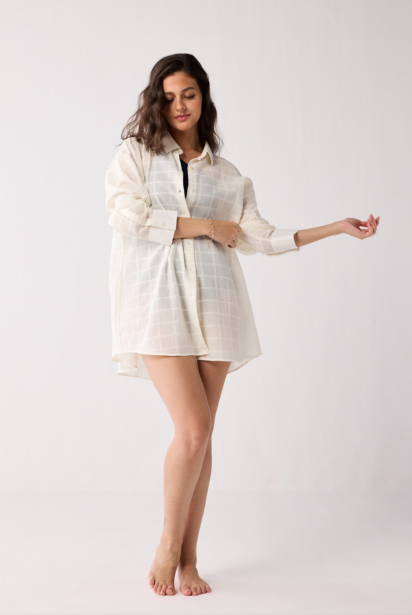 Woman wearing a light-colored cover up on a white background