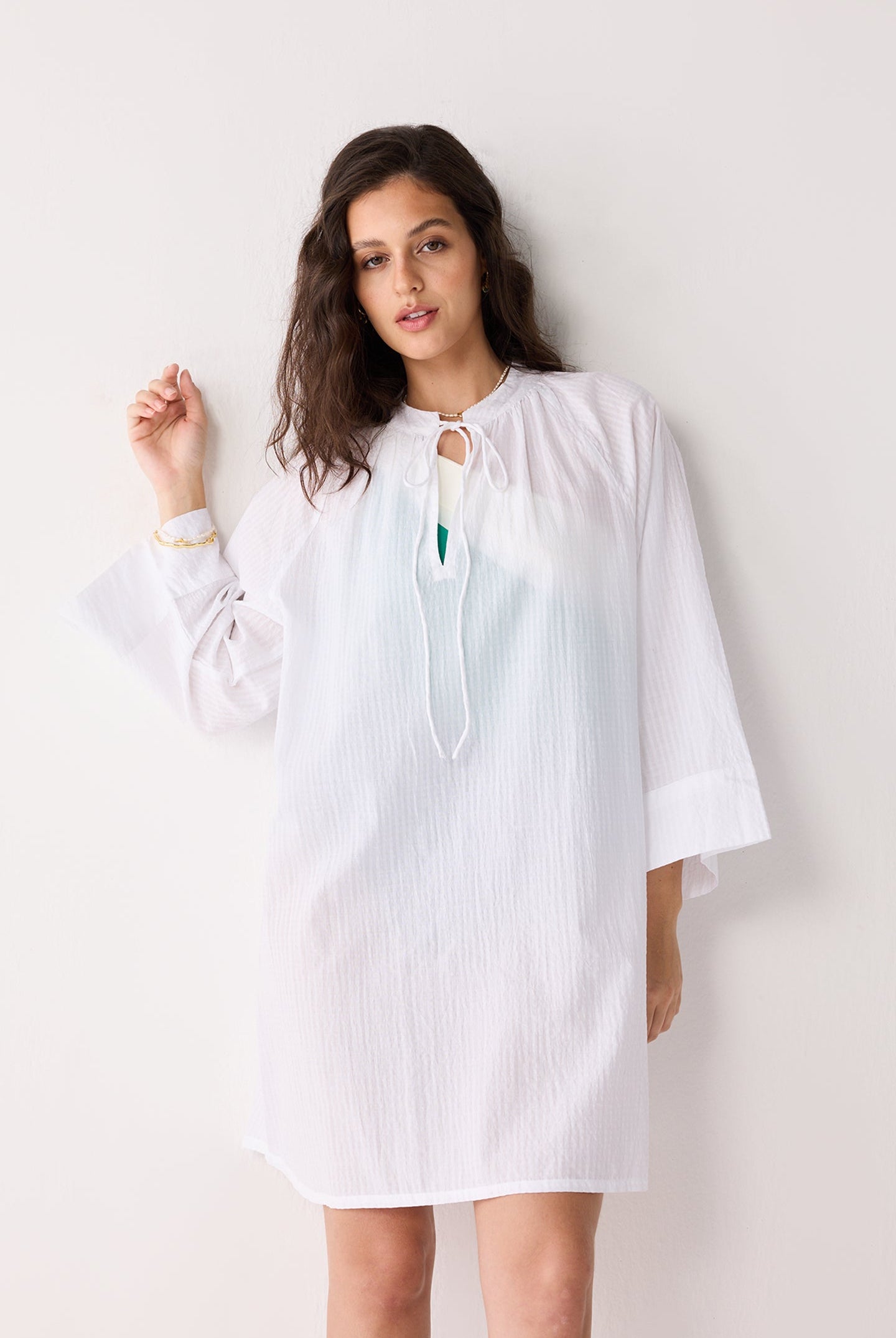 Woman wearing a white cover up with a plain background