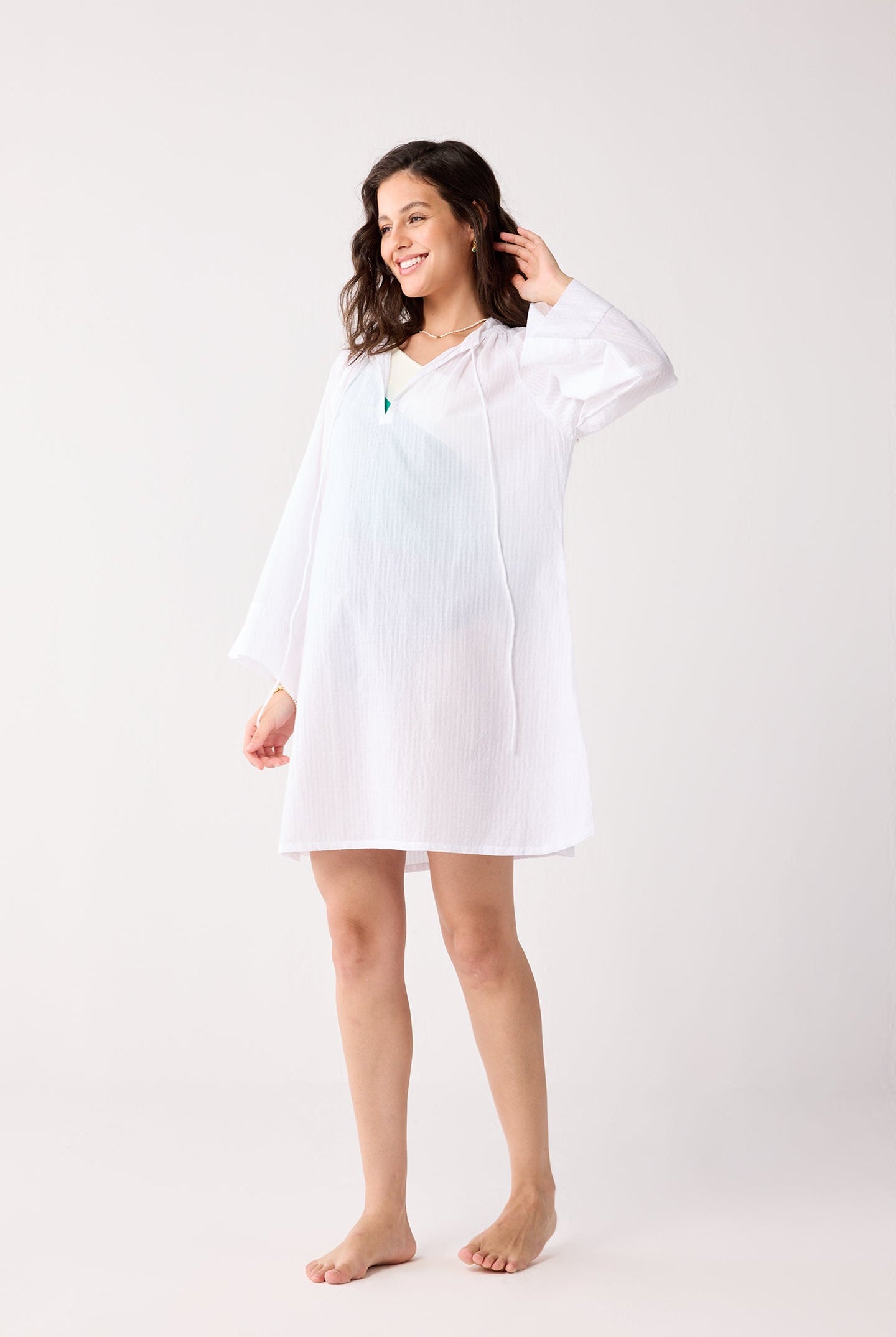 Woman wearing a white beach cover-up against a white background