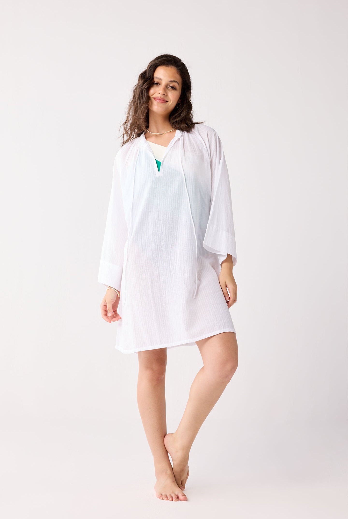 Woman wearing a white cover-up with a matching cardigan on a white background