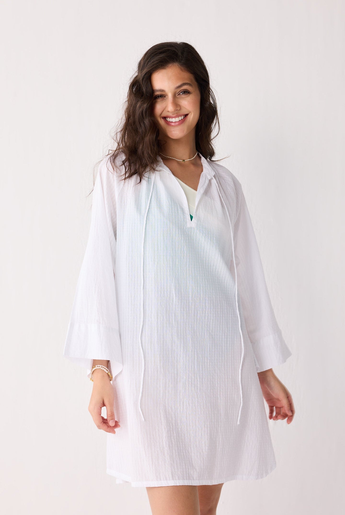 Woman wearing a white cover up against a plain background