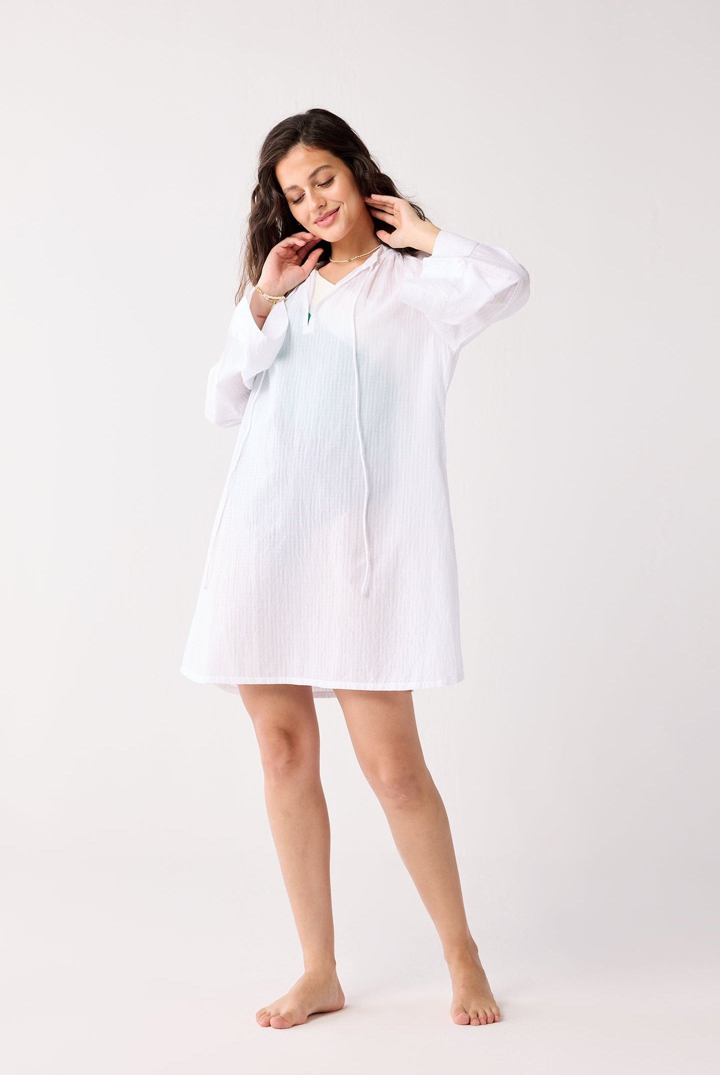 Woman wearing a white cover-up on a plain background