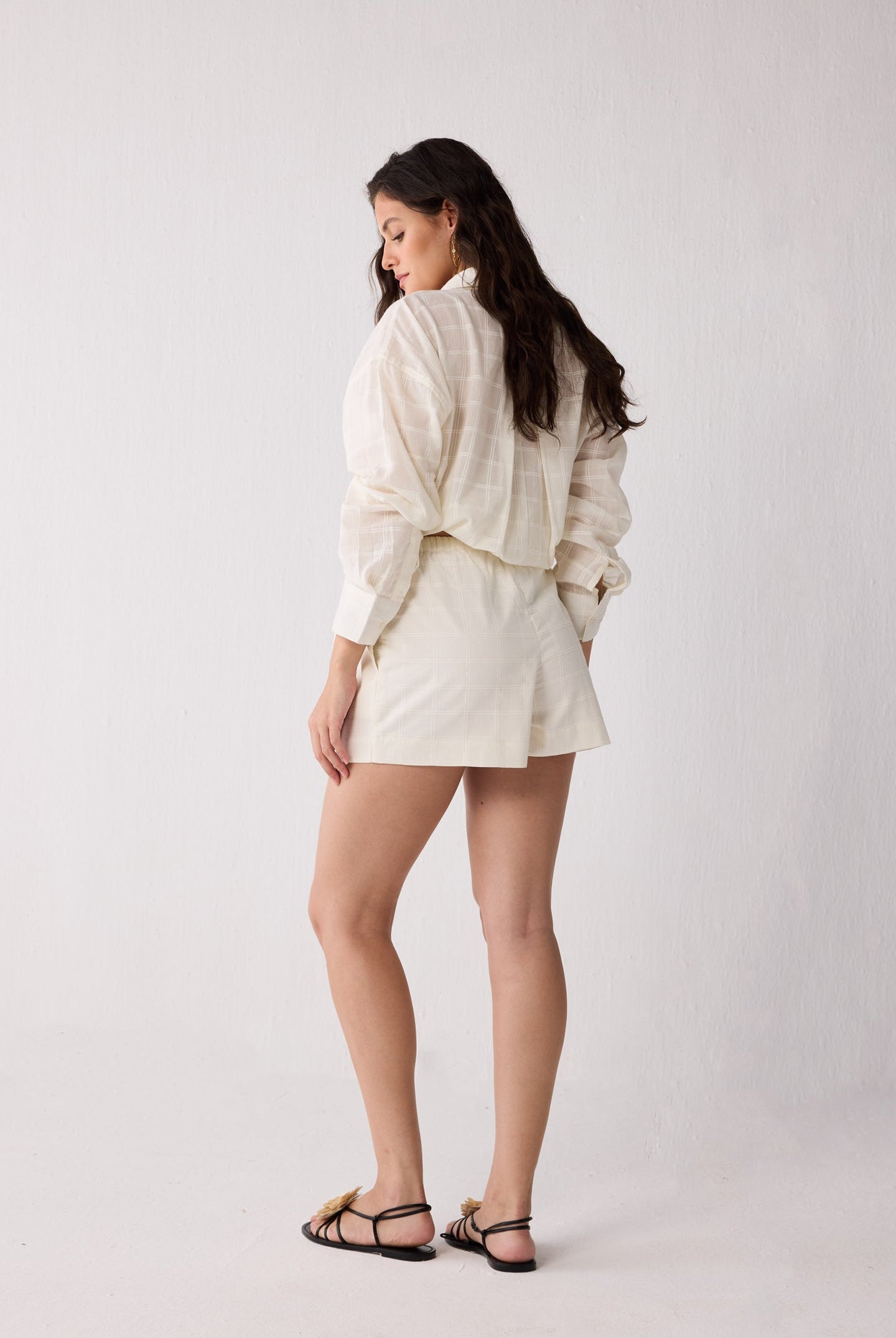 A woman wearing an off-white colored outfit on a white background