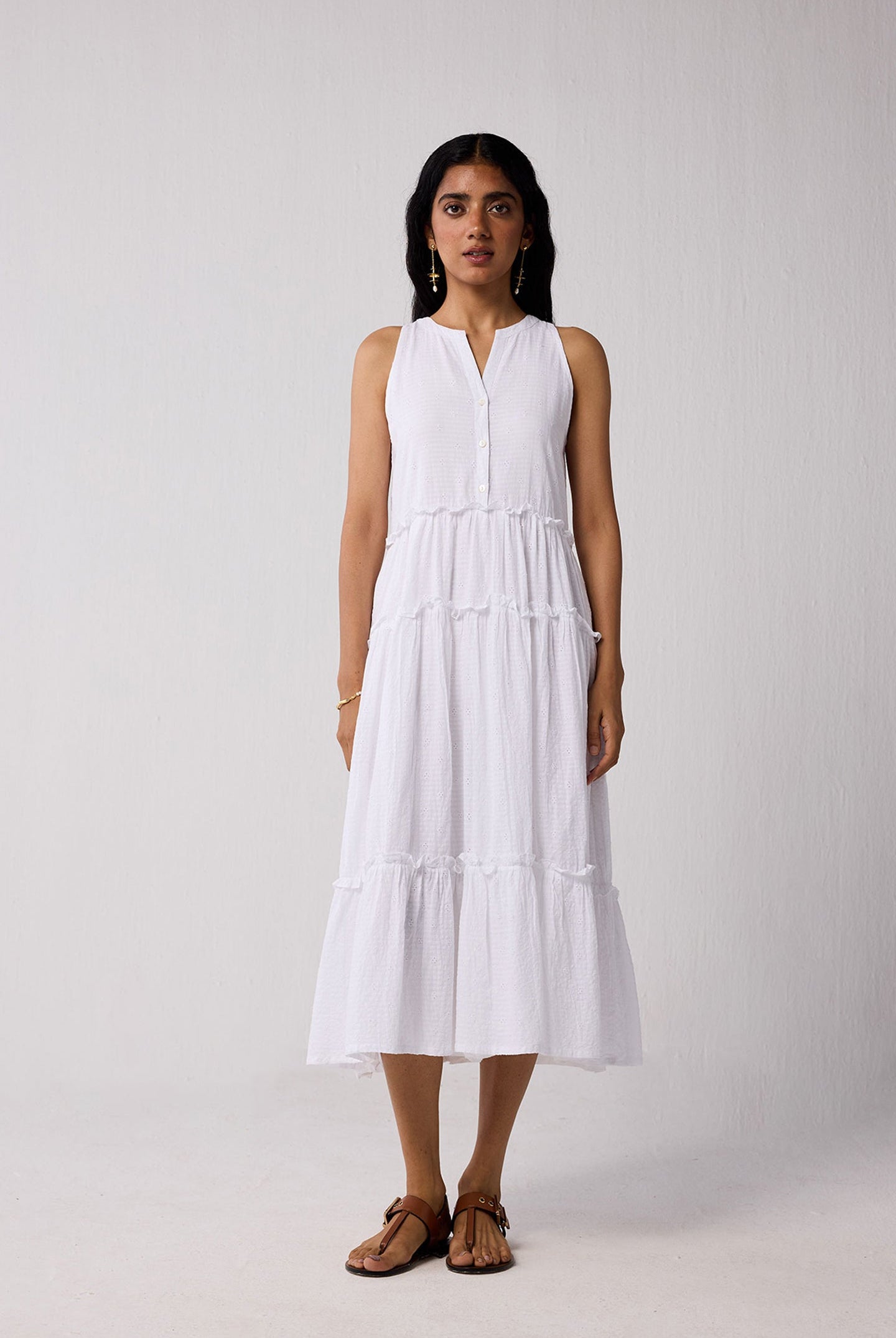 Woman wearing a white sleeveless dress on a plain background