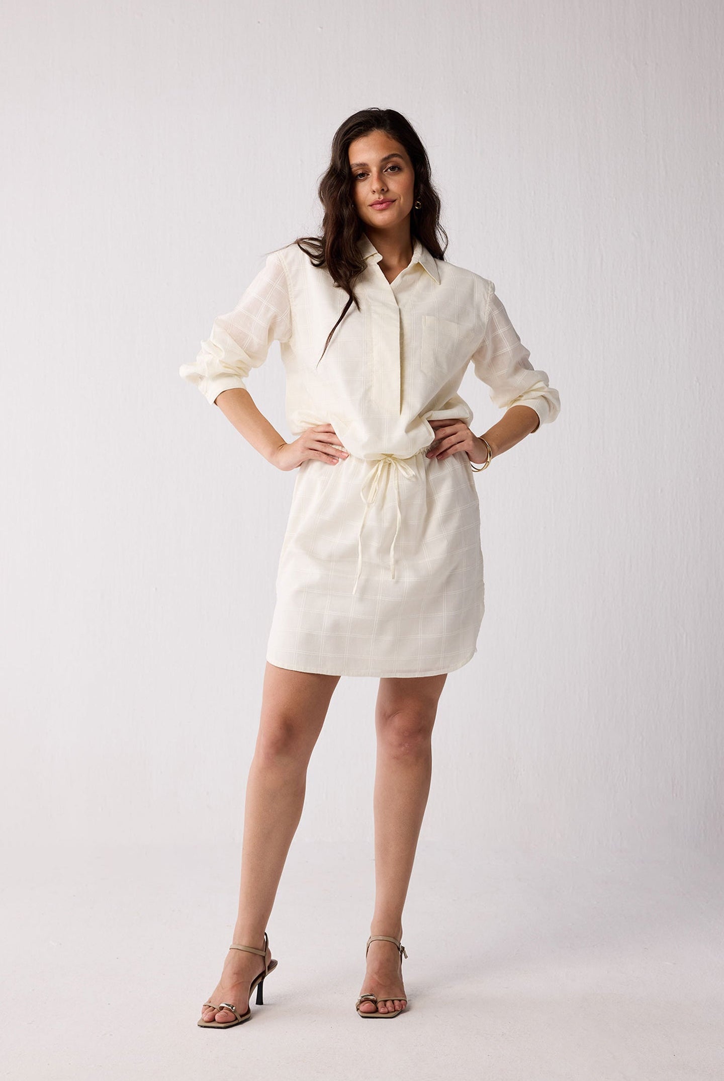 A woman wearing a white dress on a plain background