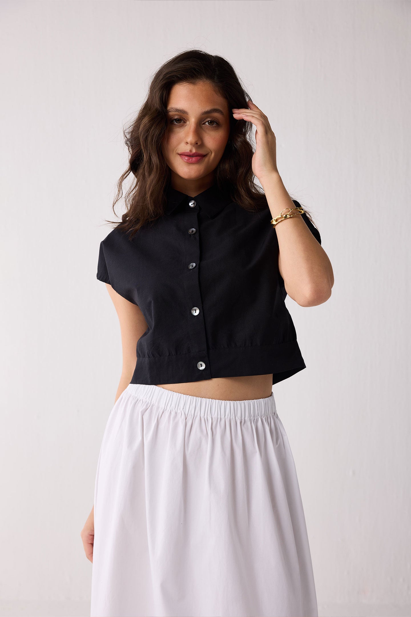 Woman wearing a black top and white skirt against a plain background