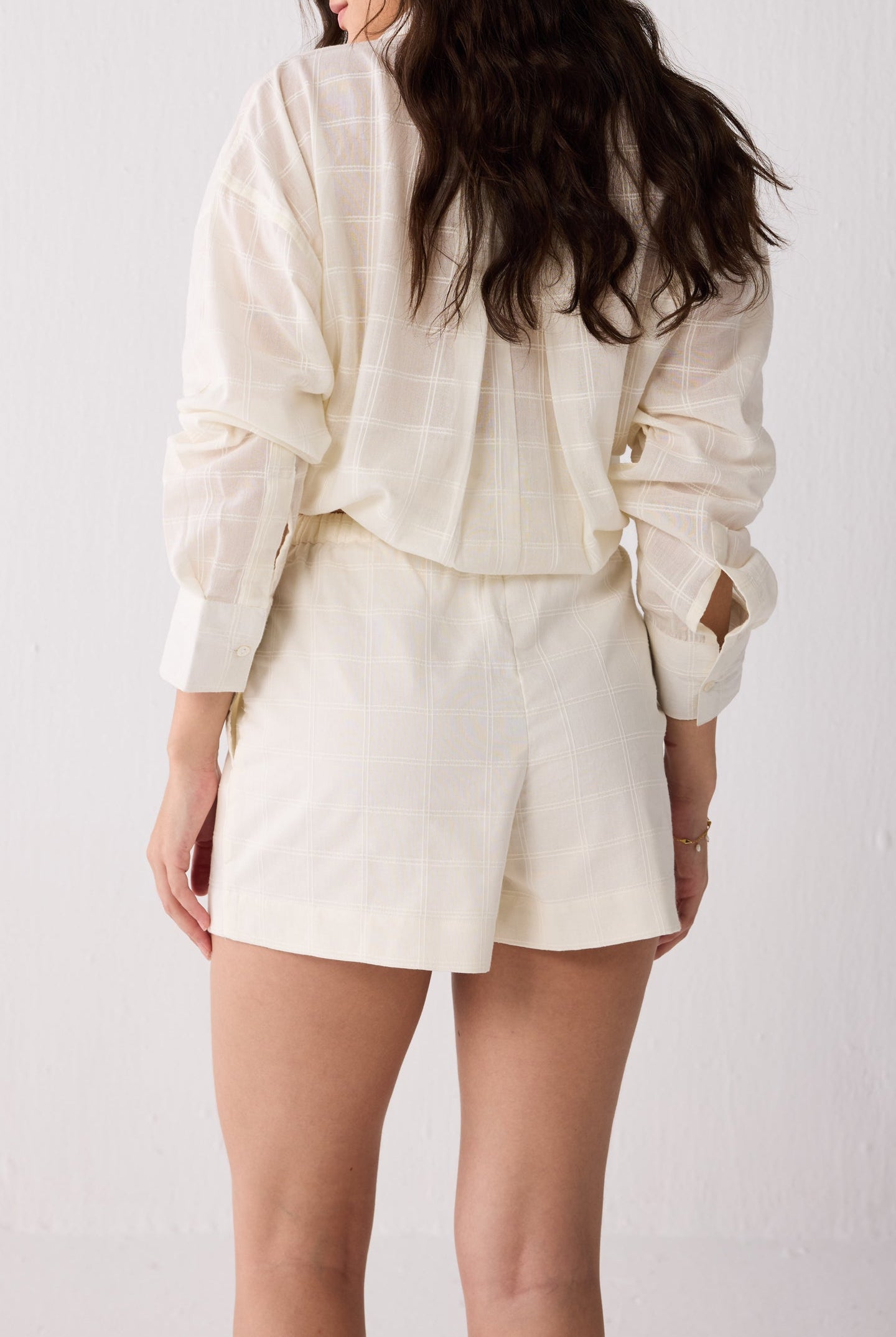 Person wearing a white outfit with a jacket and shorts on a plain background