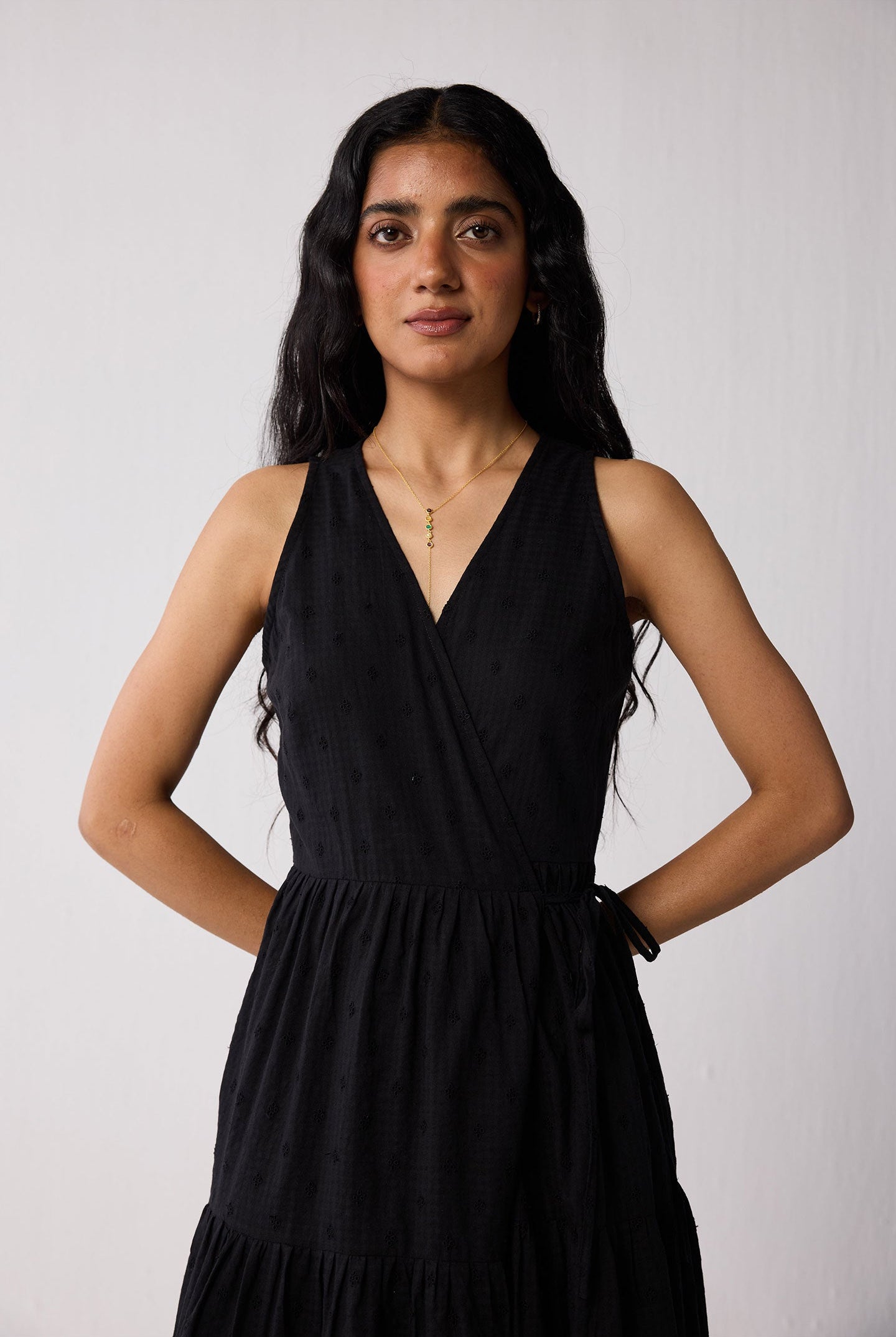 Woman wearing a black sleeveless dress against a white background
