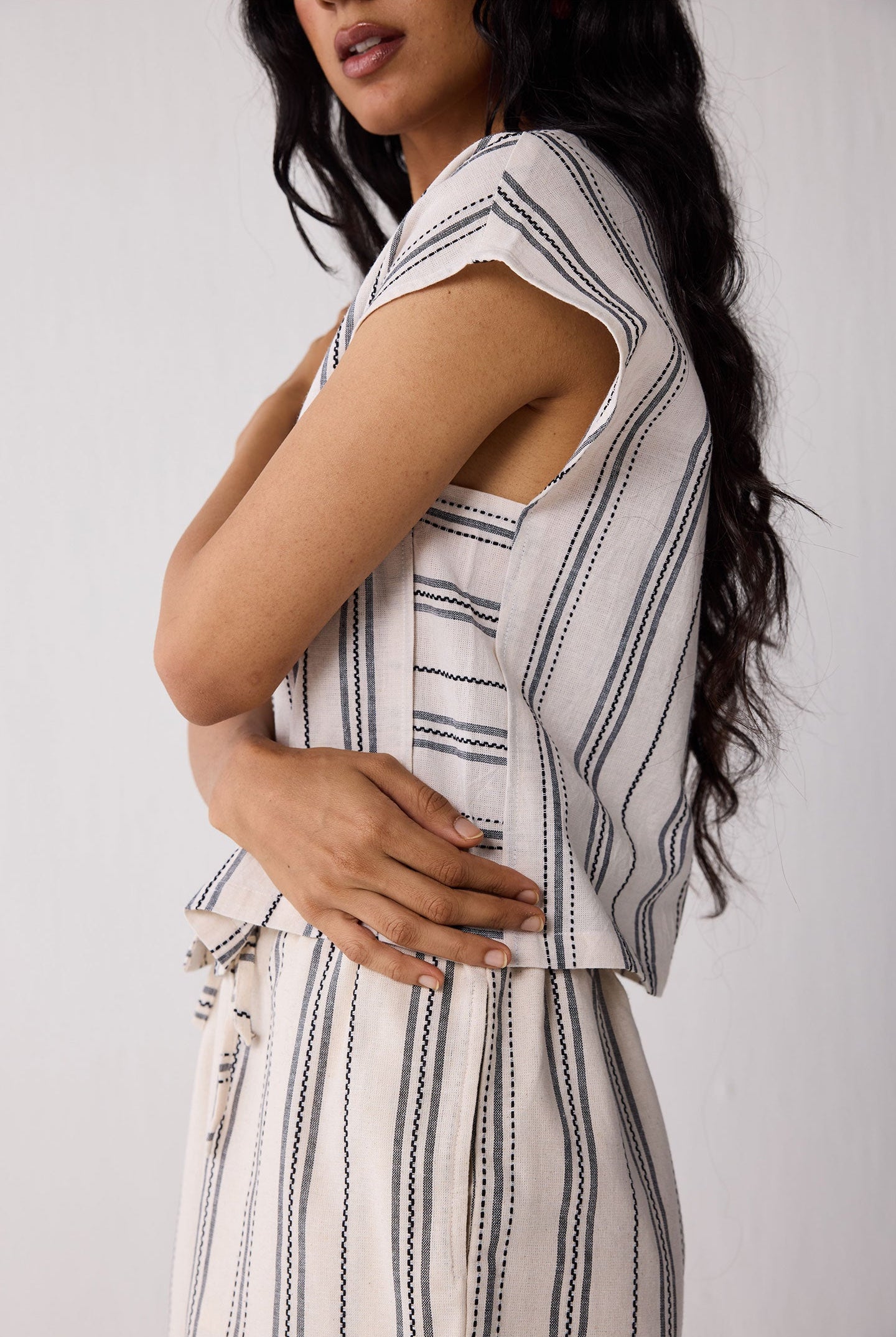 Woman wearing a sleeveless striped top and shorts against a white background