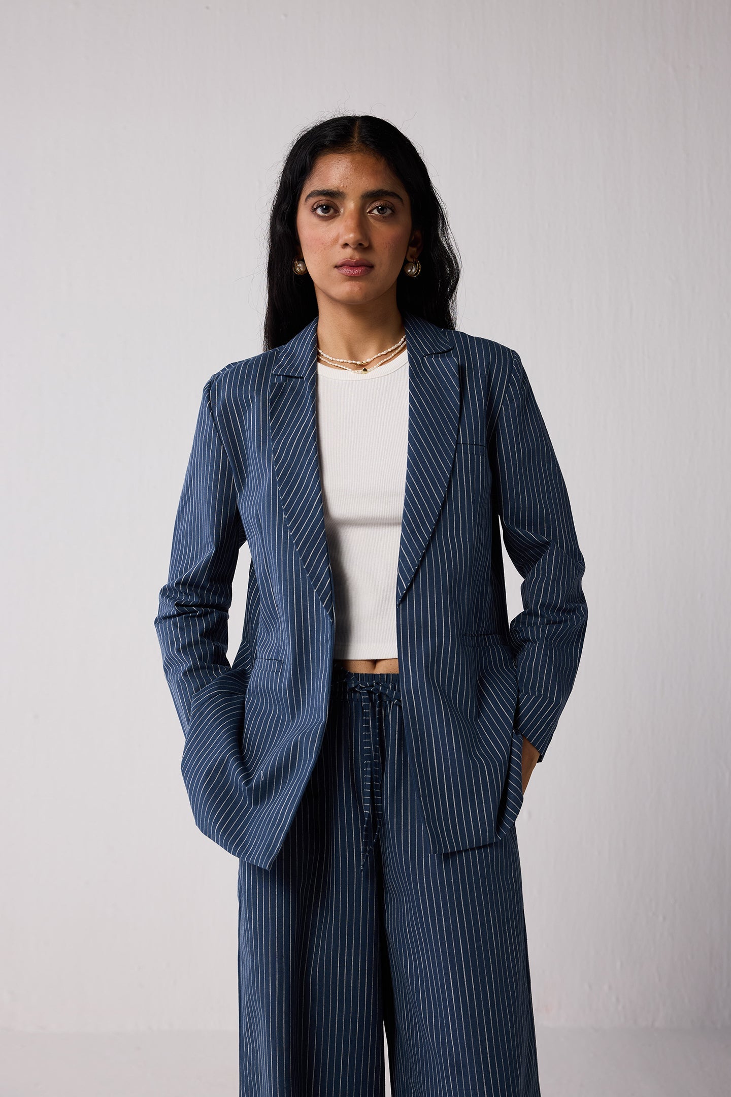 Woman wearing a blue pinstripe suit with a white top on a plain background