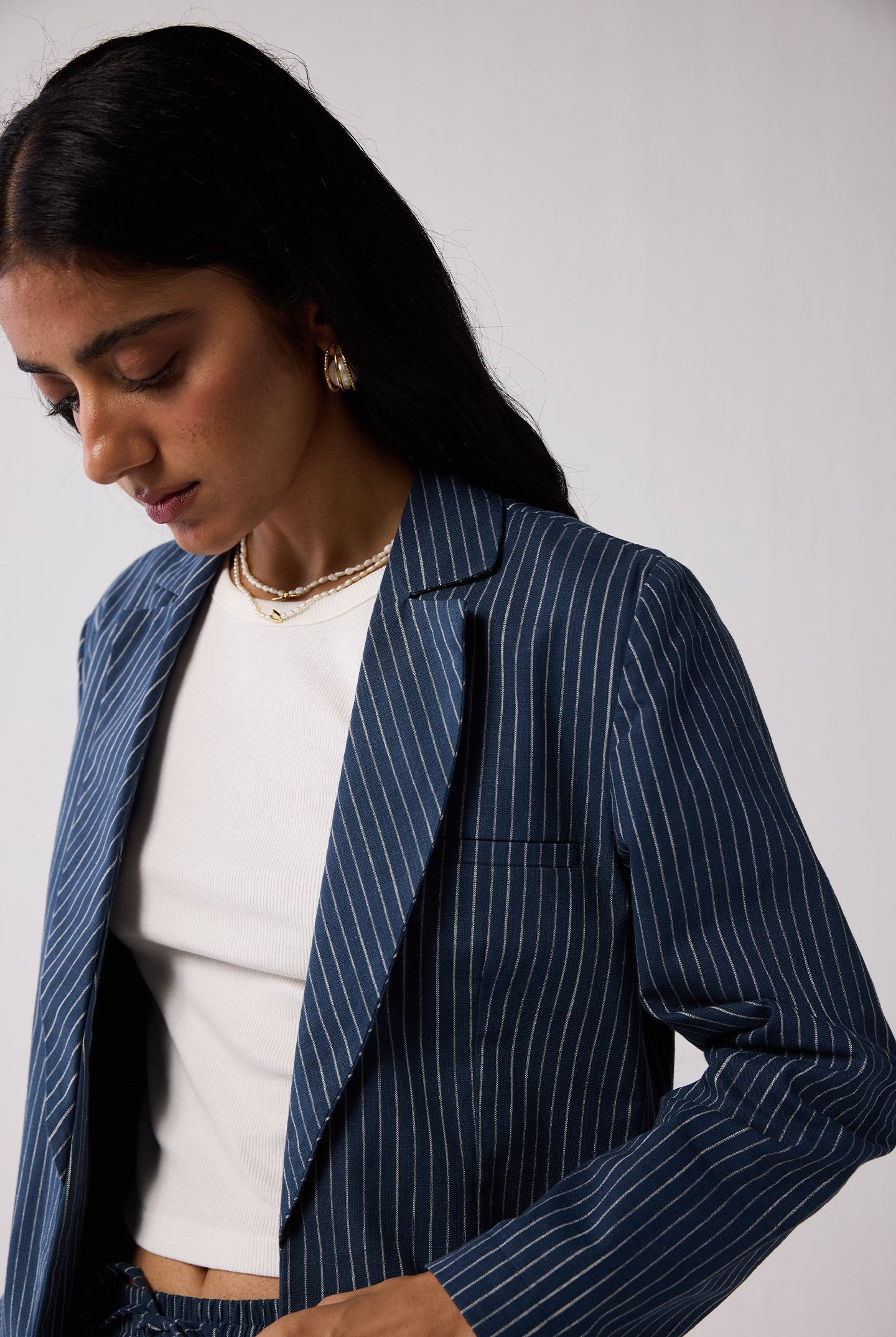 Woman wearing a blue pinstripe blazer over a white top against a plain background