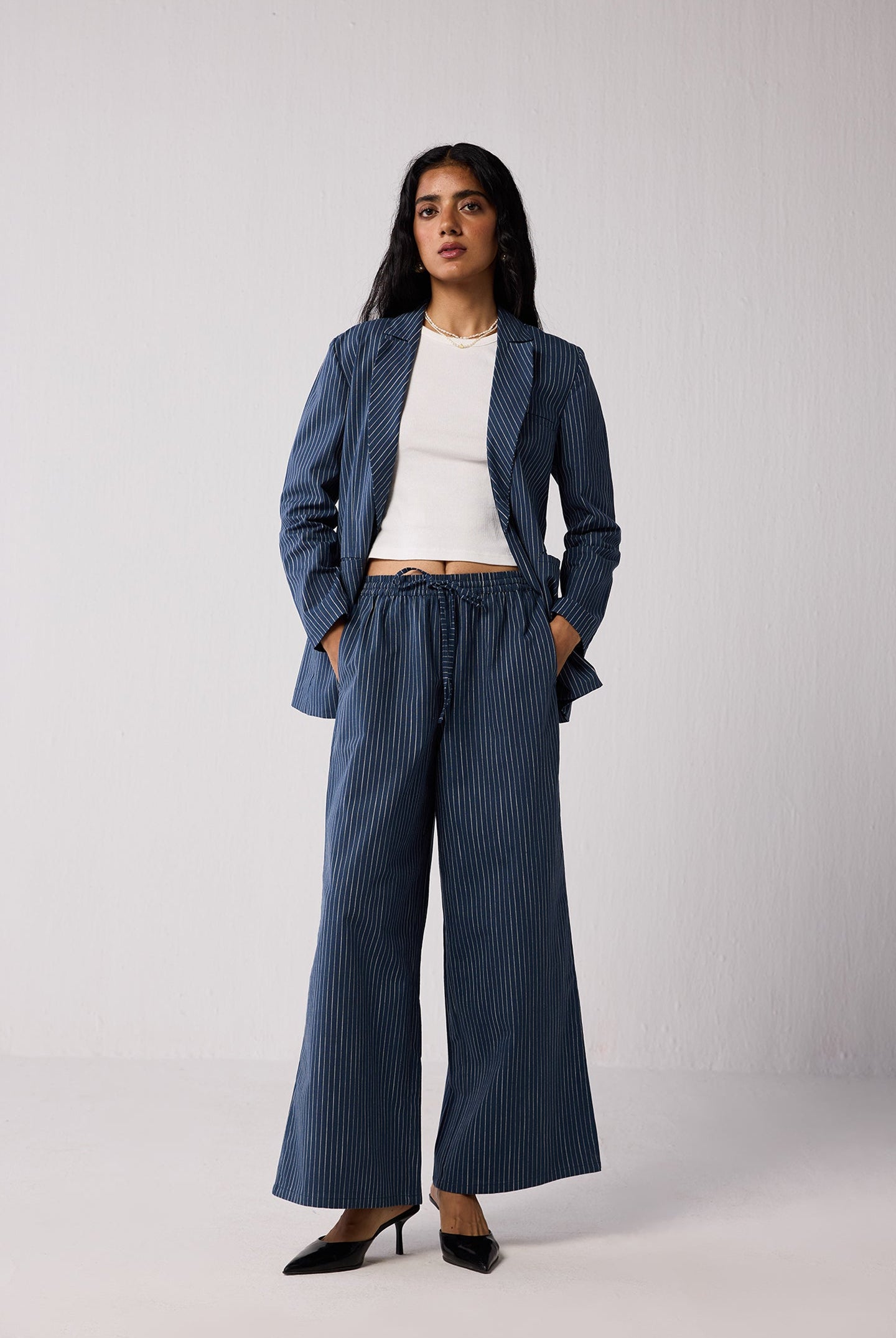 Woman wearing a blue pinstripe suit with a white top on a light background