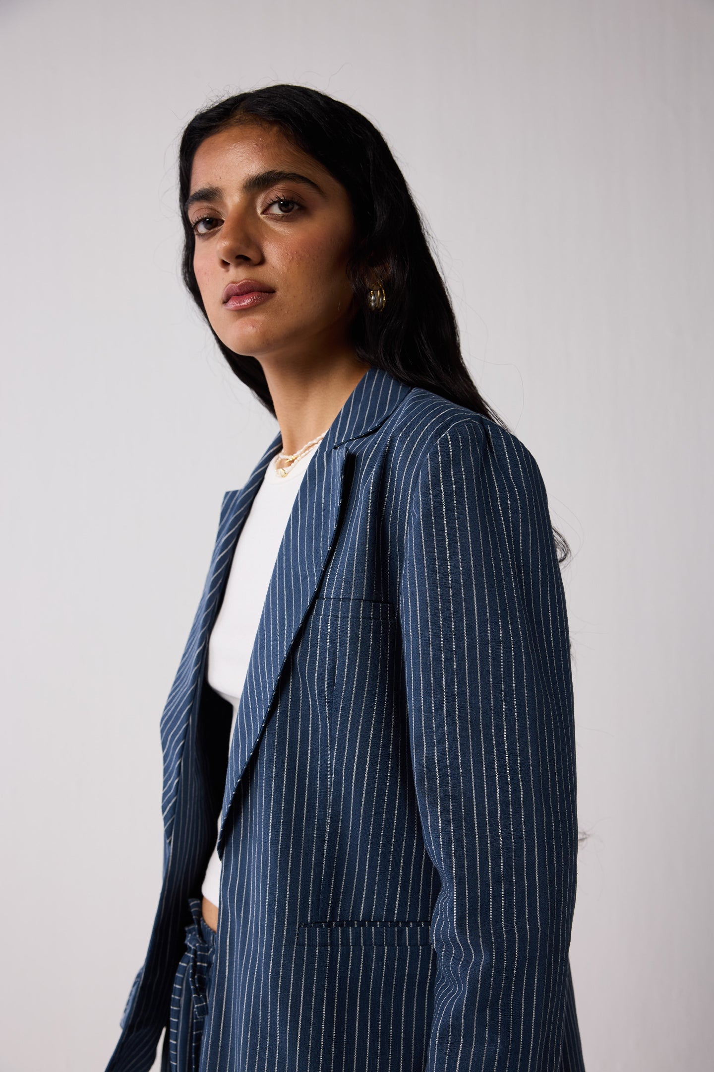 Woman wearing a blue pinstripe suit with a white top on a light background