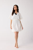 Woman wearing a white dress against a plain background