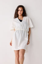 Woman wearing a white cover up against a plain background