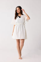 Woman wearing a white cover up against a plain background