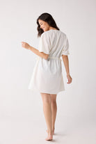 Woman wearing a white dress against a plain background