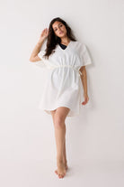 Woman wearing a white cover up on a black swimsuit on a white background