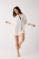Woman wearing a white shirt over a black swimsuit on a white background