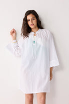 Woman wearing a white cover up with a plain background