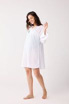 Woman wearing a white beach cover up on a plain background