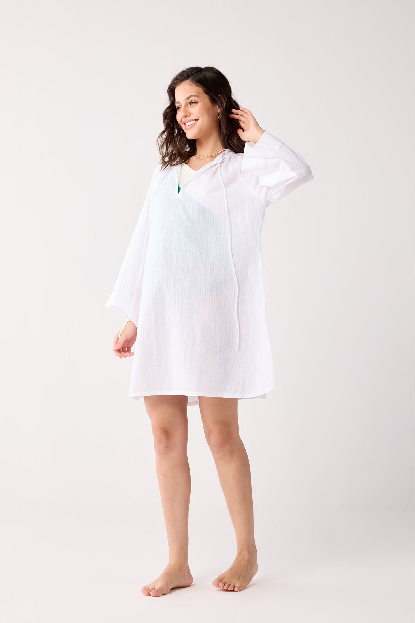 Woman wearing a white beach cover-up against a white background