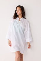 Woman wearing a light-colored cover up with a subtle pattern against a plain background