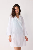 Woman wearing a white cover up against a plain background