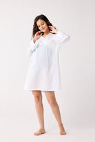 Woman wearing a white cover-up on a plain background