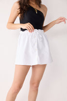 Person wearing a black top and white shorts on a plain background