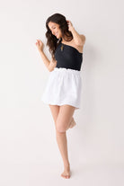 Woman wearing a black top and white skirt on a white background
