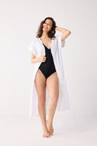 Woman wearing a black swimsuit with a white cover-up on a white background