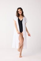 Woman wearing a black swimsuit with a white cover-up on a white background