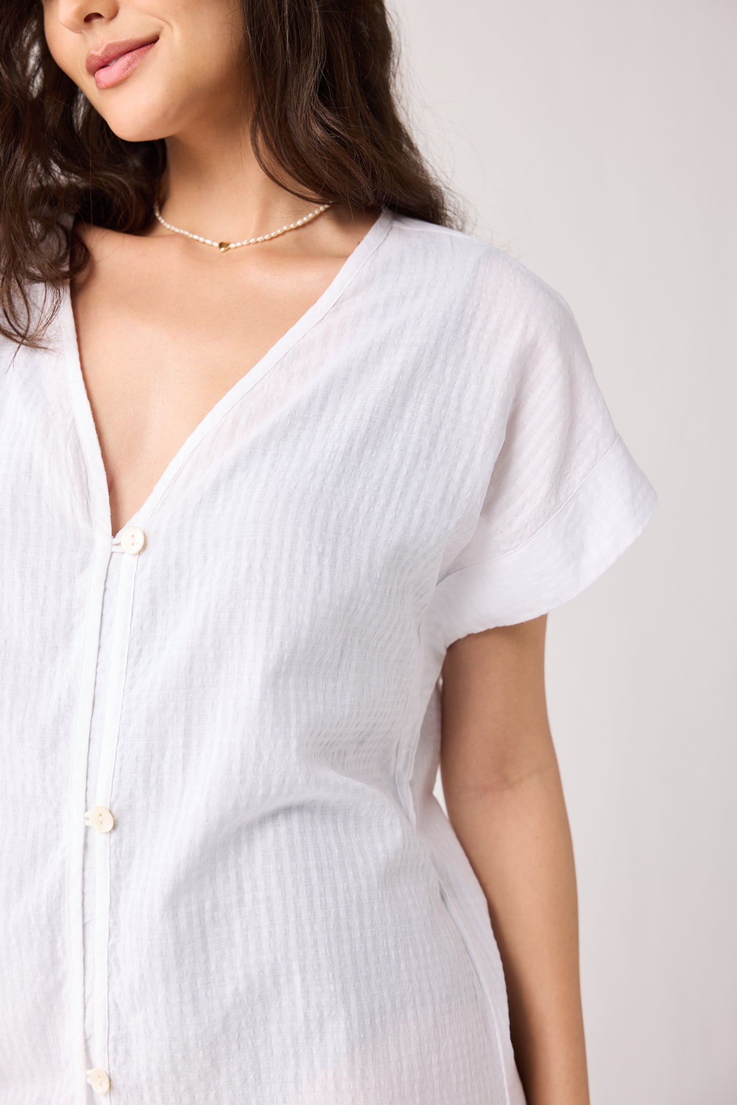 Woman wearing a white button-up shirt against a plain background