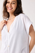 Woman wearing a white blouse against a plain background