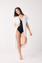 Woman wearing a black swimsuit with a white cover-up on a white background