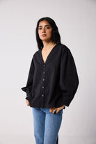 Woman wearing a black shirt and blue jeans against a white background