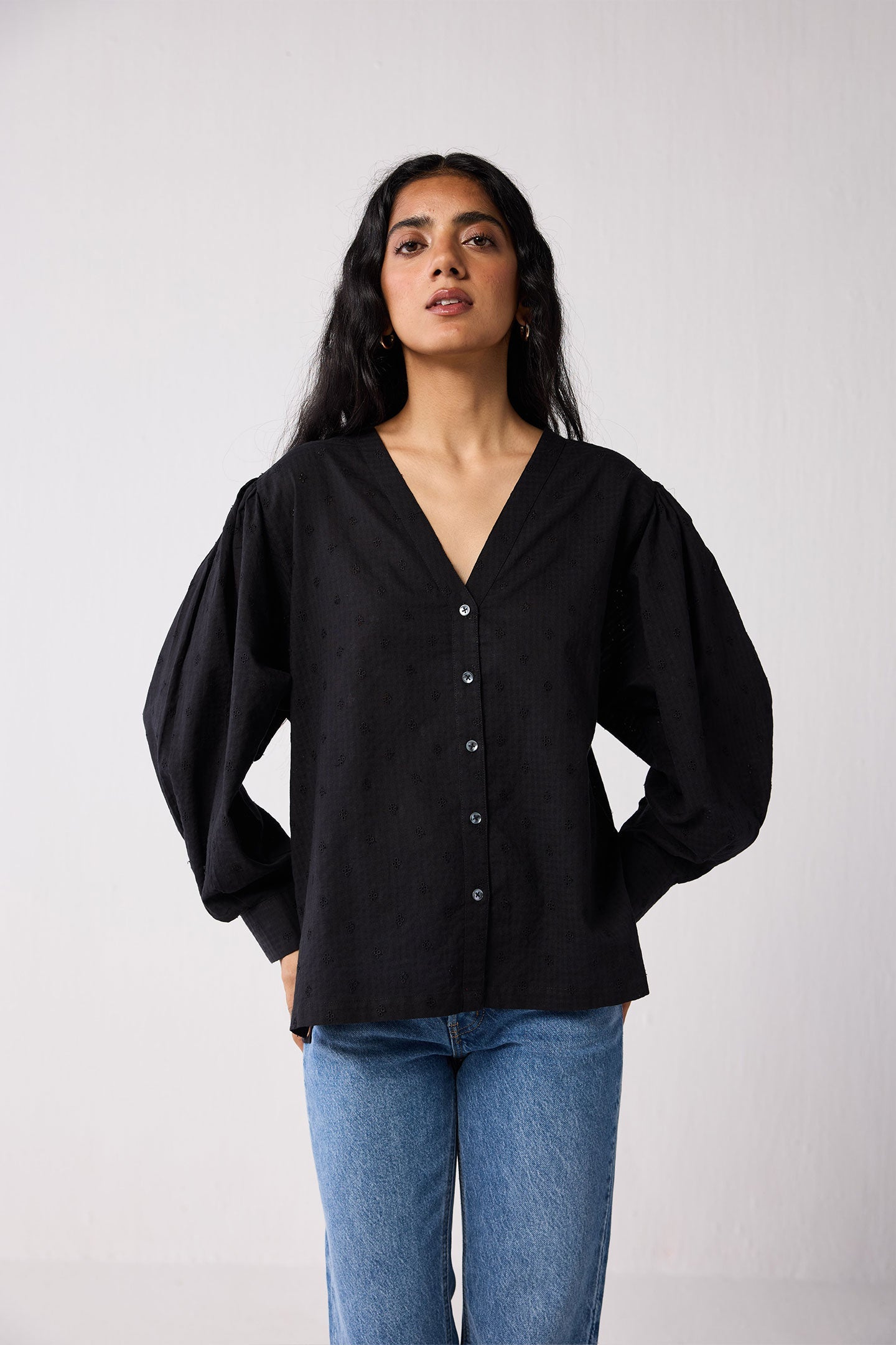 Woman wearing a black blouse and blue jeans against a white background