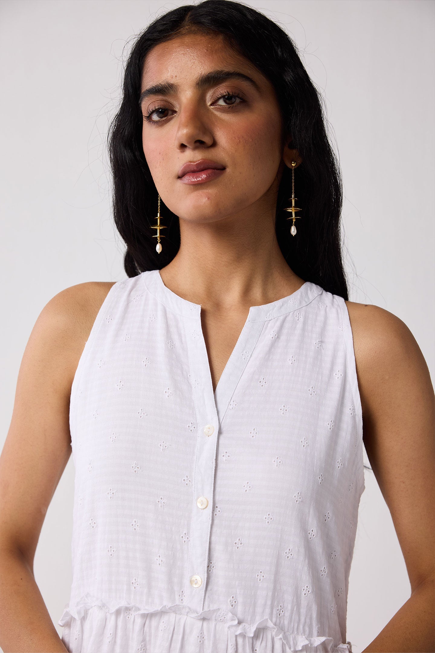 Woman wearing a white sleeveless top with a plain background