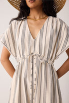 Woman wearing a beige and black striped dress with a plain background