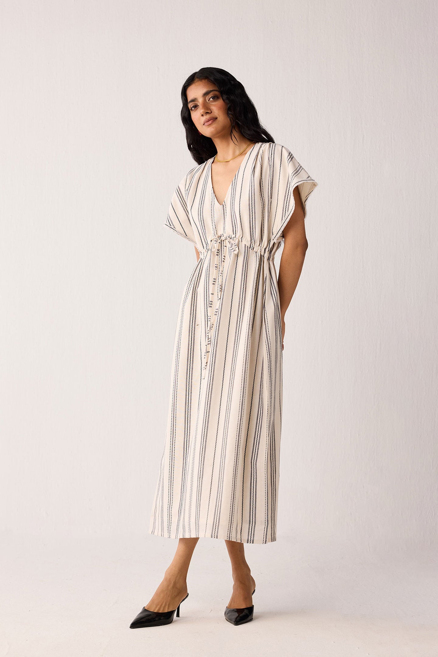 Woman wearing a white and beige striped dress against a white background