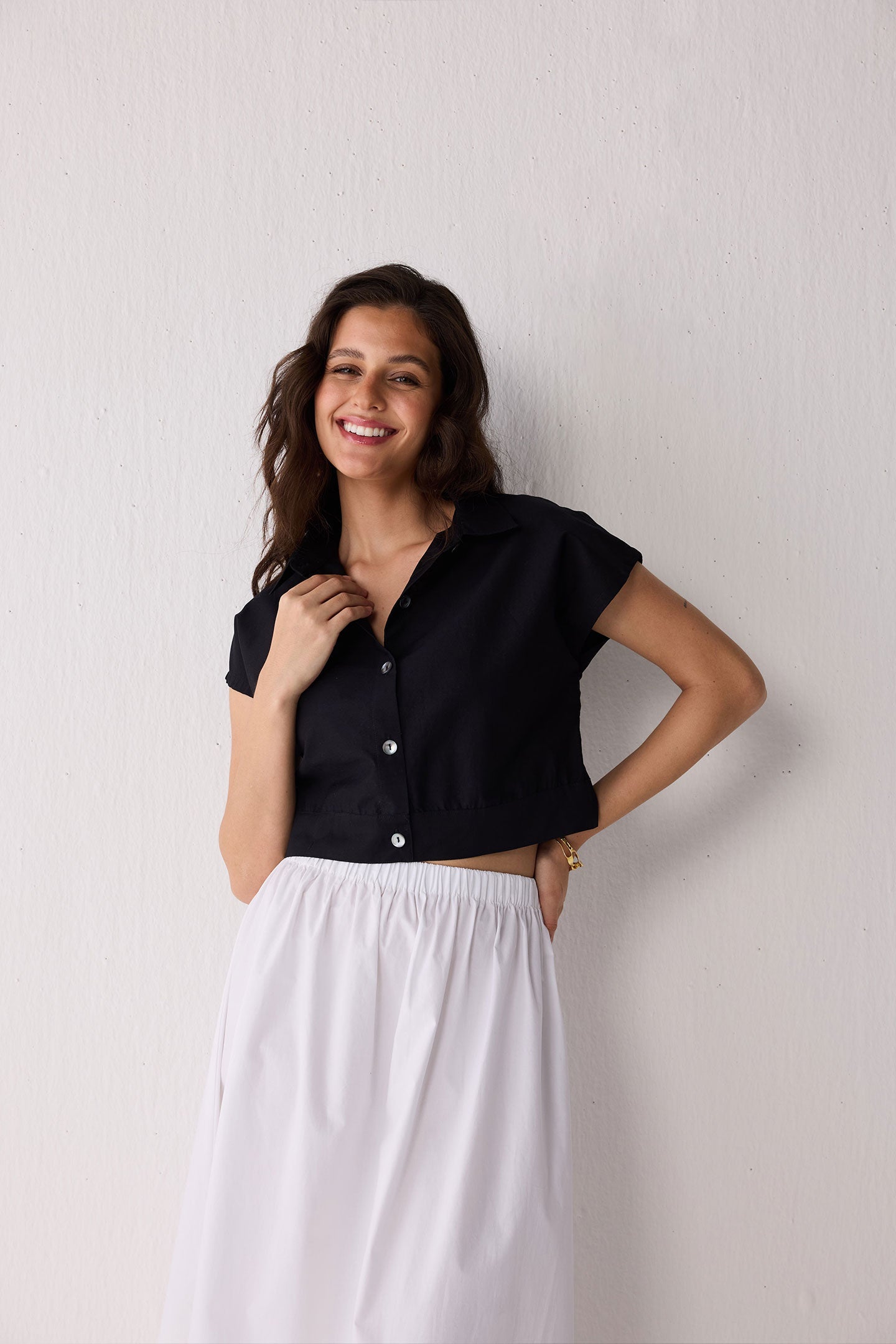 Woman wearing a black top and white skirt against a plain background