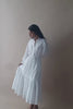 The model presents multiple poses in a Reistor embroidered flowy maxi tiered dress in white, standing to reveal the fine, lightweight fabric and embroidered detailing, then twirling to emphasize the dress’s layered tiers, soft drape, and elegant motion.